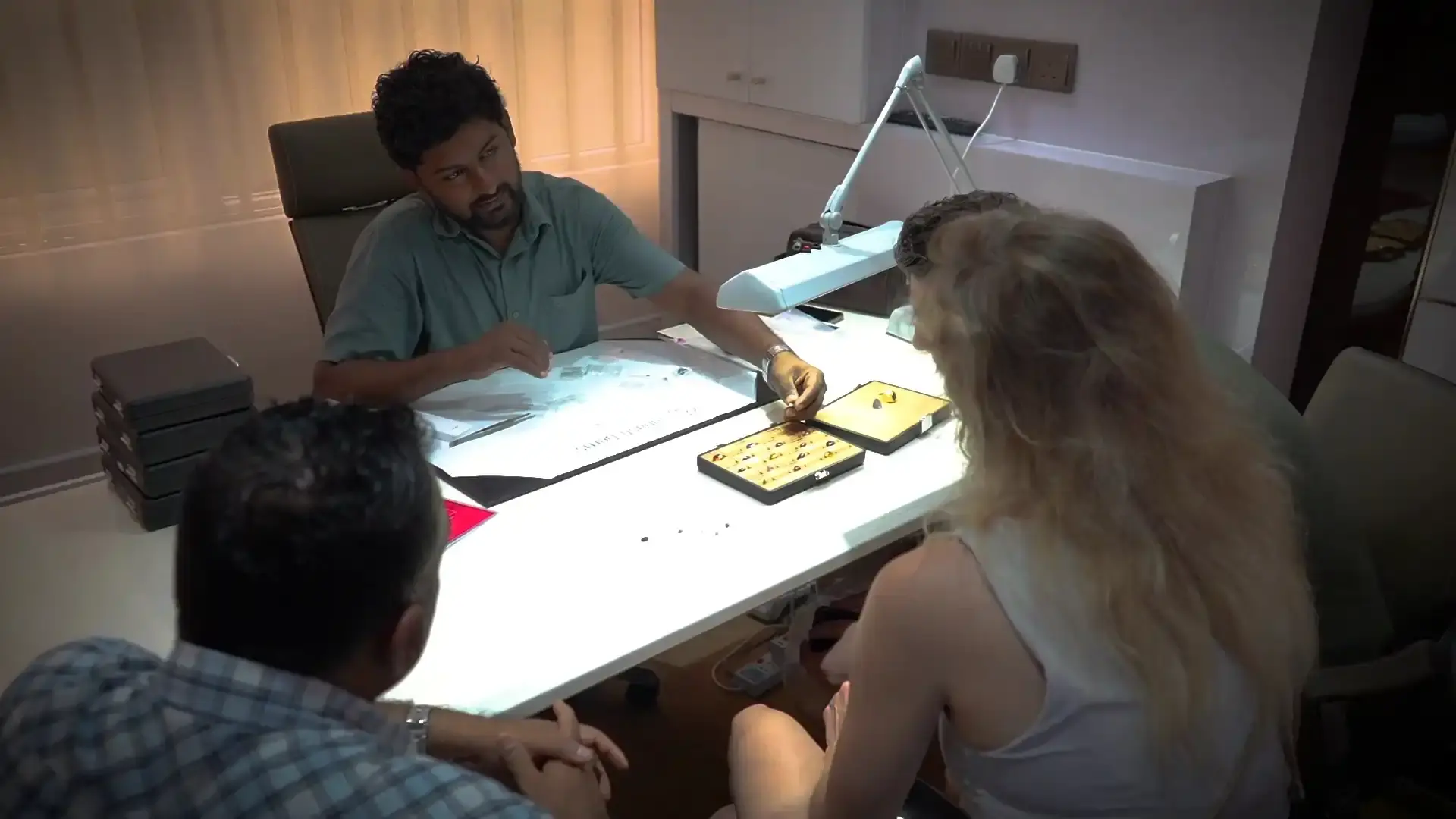 A gemologist sorts and grades small gemstones at a well-lit desk.